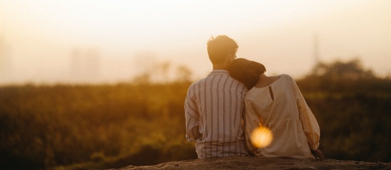 Couple sitting near grass field