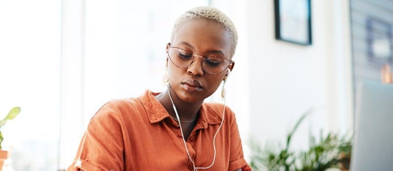 Young woman wearing earphones while working