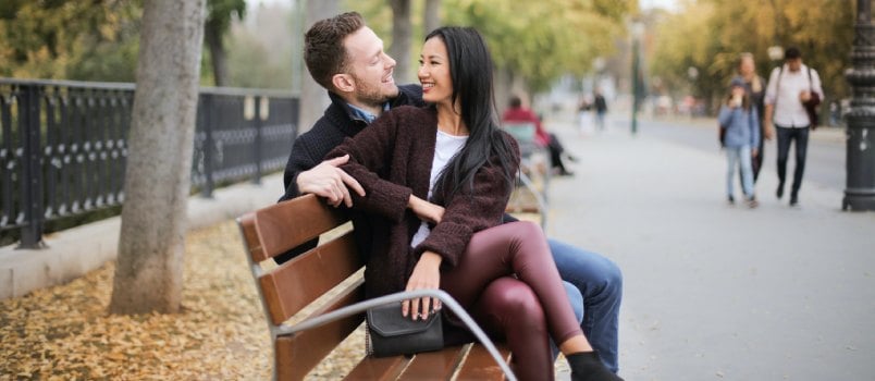 Couple talking while sitting on wooden bench