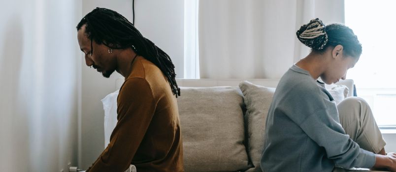 Couple sitting on bed having misunderstanding