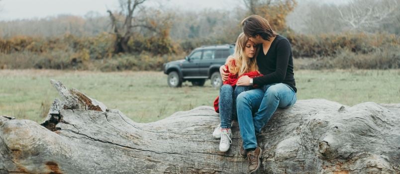 Man and daughter sitting on wood log