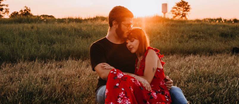 Couple sitting beside green field