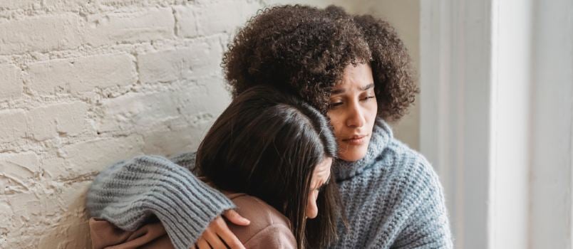 Sad woman hugging at home