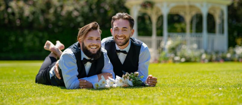Happy gay couple laying on grass
