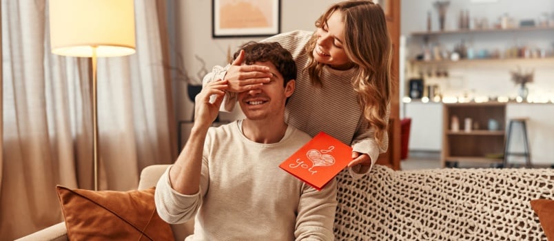 Woman surprising man with gifts