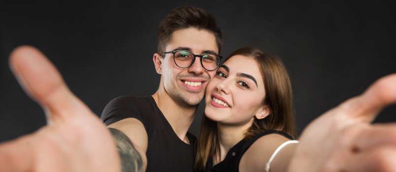 Happy couple taking selfie on white background