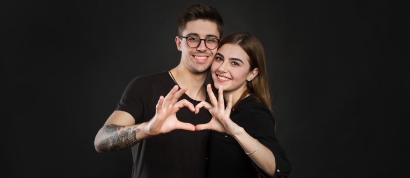 Happy couple making heart shape with fingers