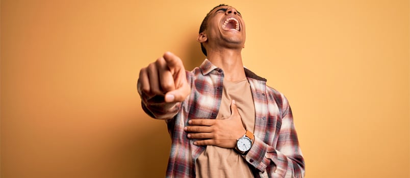 Young man laughing pointing towards camera