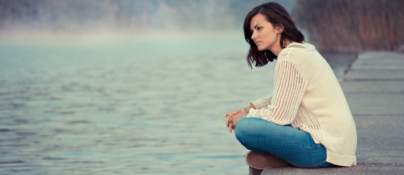 Girl sitting by lake