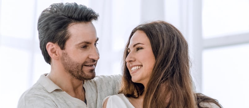 Happy couple standing by the window