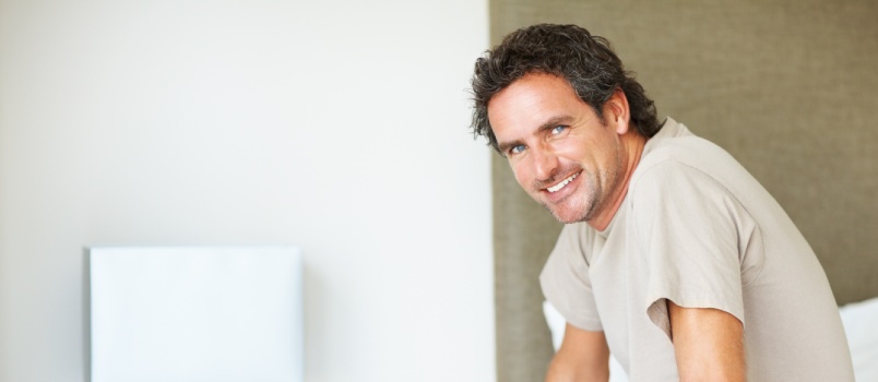 Handsome man sitting on bed giving smile