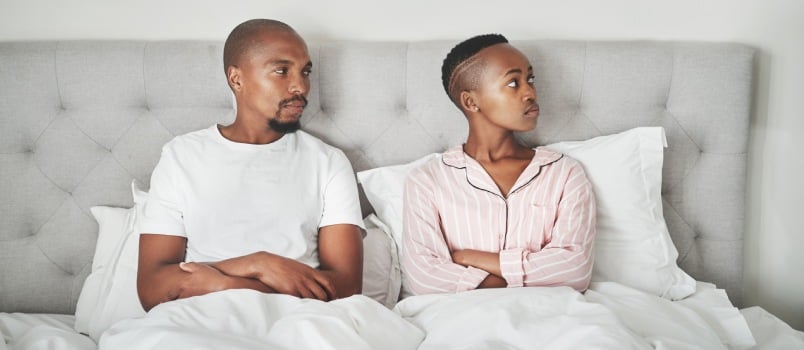Couple ignoring each other in bed