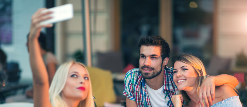 Young friends taking selfie at cafe
