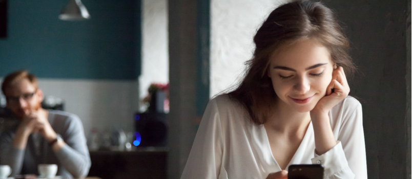 Man looking at woman while she is using phone