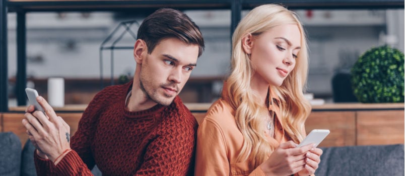 Young couple sitting using smartphone