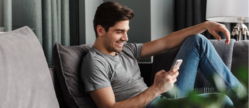 attractive smiling young man using smartphone