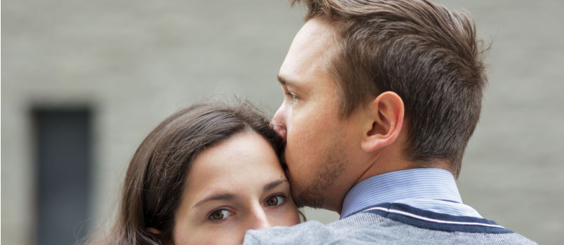 Man kissing on woman forehead