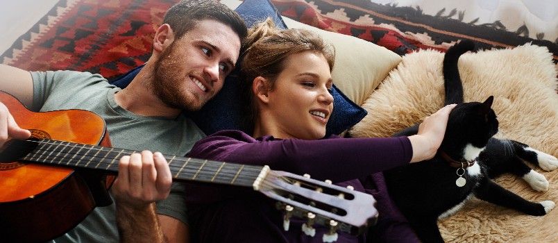 Man playing guitar while laying on floor with his girlfriend