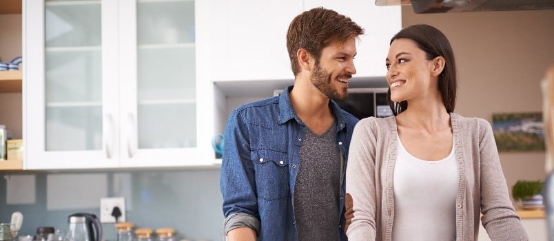 Happy couple looking at each other standing in kitchen