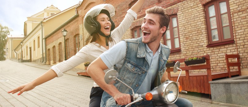 Happy couple riding scooter in town
