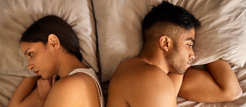 Couple ignoring each other on bed