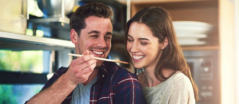 Happy man feeding his women in kitchen