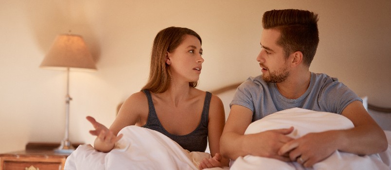 Couple sitting in bed talking to each other