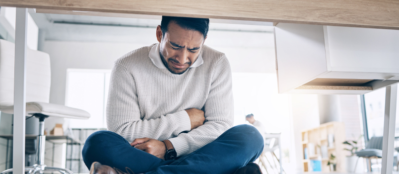 Man sitting under table crying