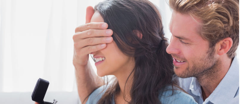 Man hiding his wife eyes and giving rings