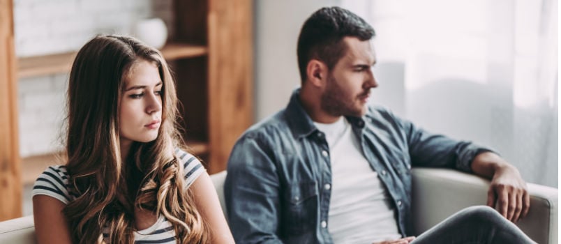 Upset couple sitting at couch