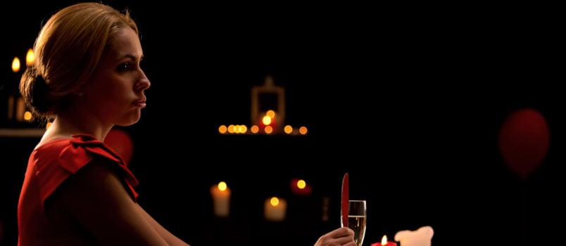 Unhappy woman sitting alone in restaurant