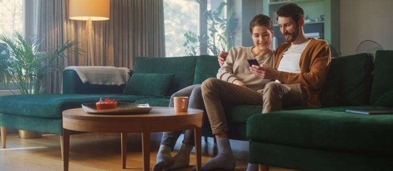 Couple smiling while using smartphone