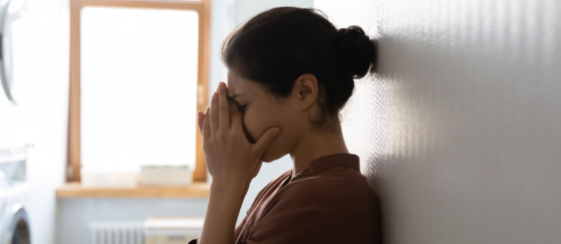 Young woman leaning on the wall crying