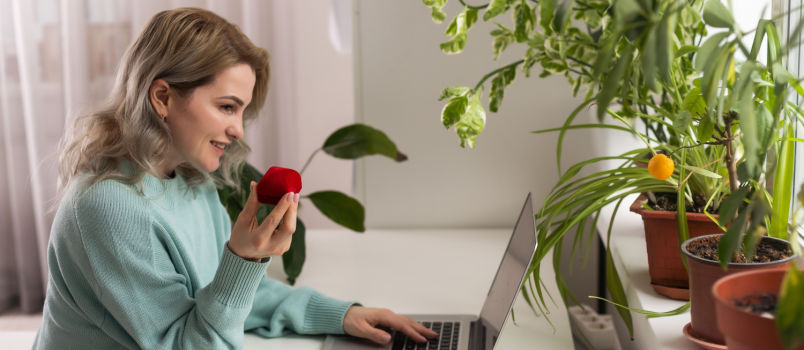 Girl having ring box while browsing on laptop
