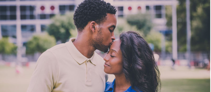 Young man kissing woman on forehead