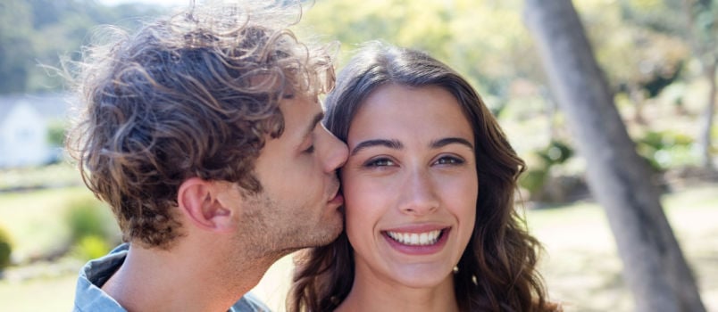 Man kissing woman on checks
