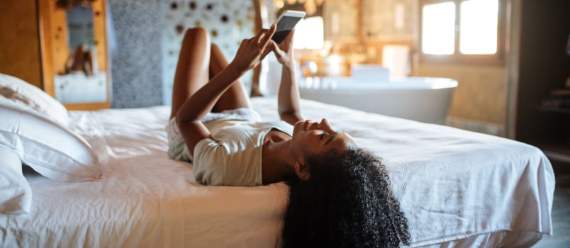 Woman laying down on bed using phone
