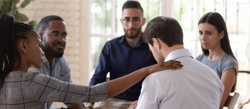 people consoling upset man
