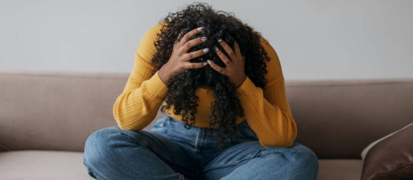 Depressed young woman sitting on couch