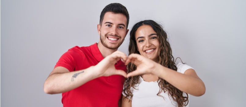 Young happy couple making heart with hands