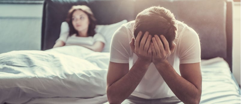 Upset man sitting on bed