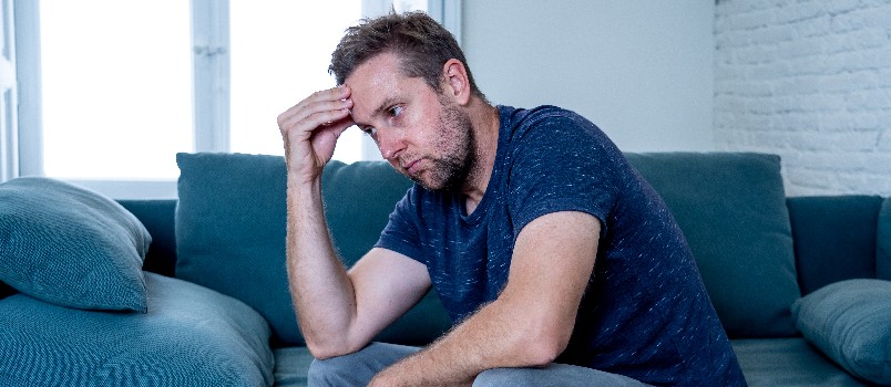 Unhappy depressed man sitting on couch