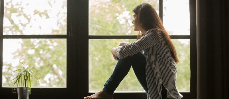 Thoughtful woman sitting beside the car