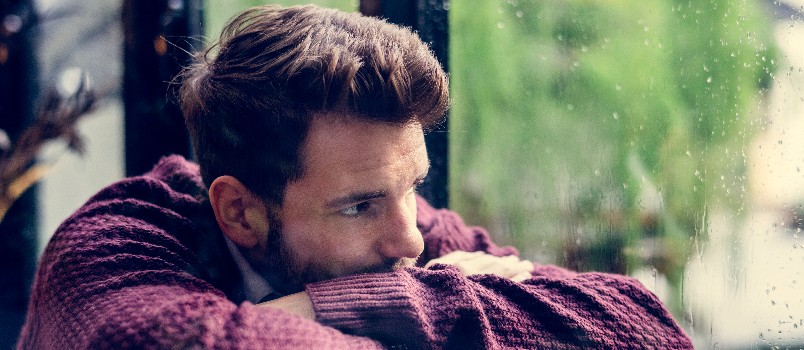 Thoughtful man looking outside of window