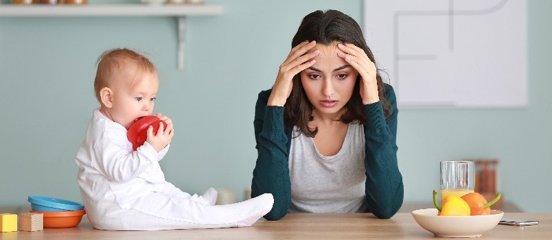 Depressed woman sitting while baby is playing 