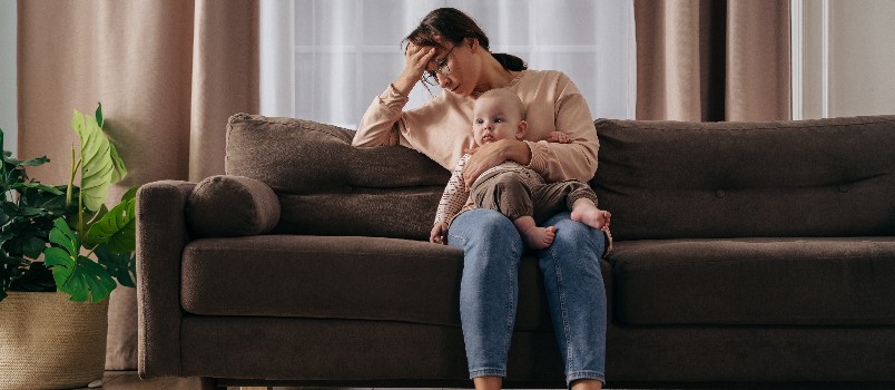 Woman sitting on sofa holding baby 