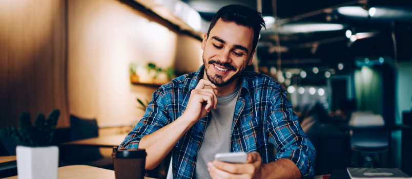 Young man smiling while reading the messages 