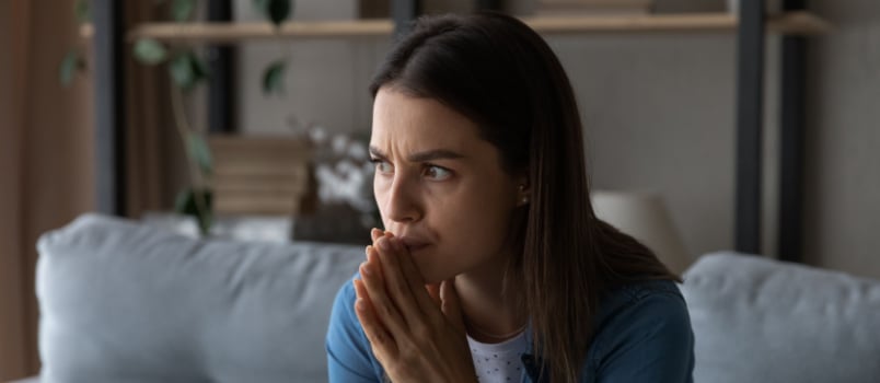 Worried young woman sitting in couch 