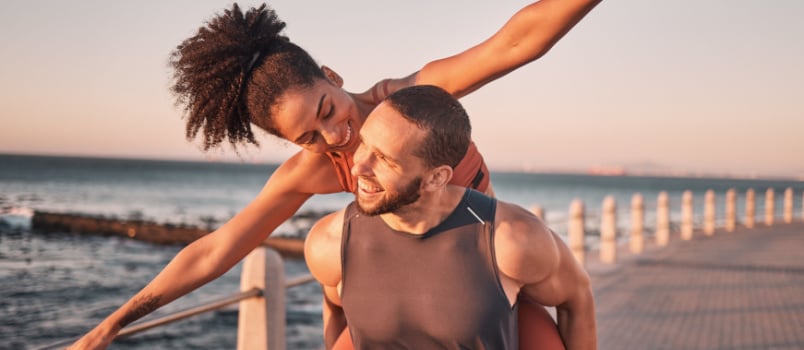 Beach fitness couple piggyback sunset