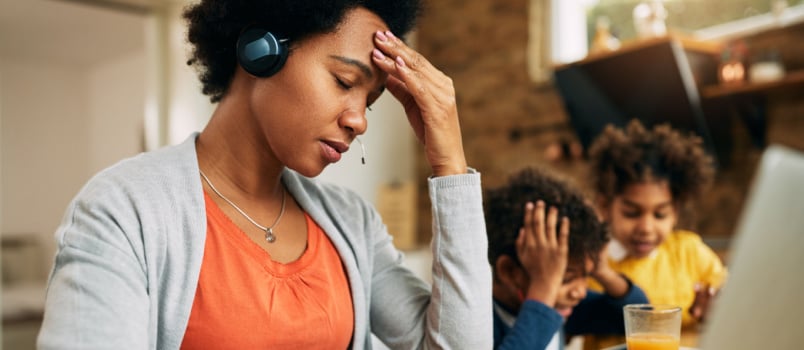 Depressed mother working while kids playing 